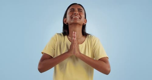 Oración, manos y deseo femenino con esperanza sobre fondo azul en el estudio con ansiedad o gesto