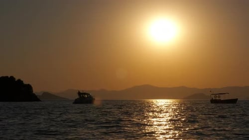 Sunset on Ocean with Boats and Distant Mountains