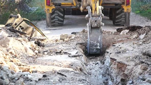 Excavator Digs a Trench to Lay Pipes