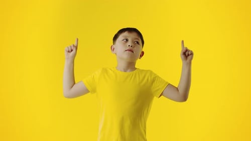 Young Child Points Upwards on Yellow Background
