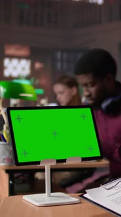 Vertical Video University Scholar Writes Project Ideas Next to Green Screen on Tablet