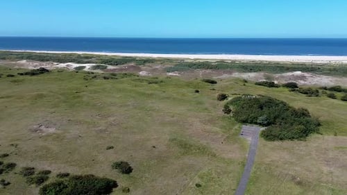 Top view of the beach kijkduin and sea. Flight over fields with green grass and buildings on the sea