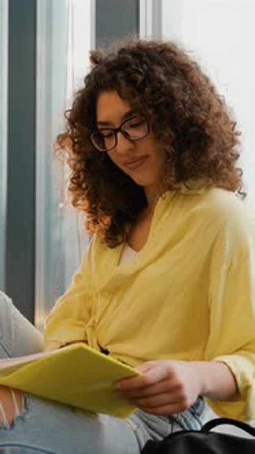 Young Female Student Reading Notes in a Library