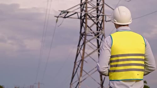 Control engineer with tablet pc, power lines and pylons, discussing expansion plan and energy transp