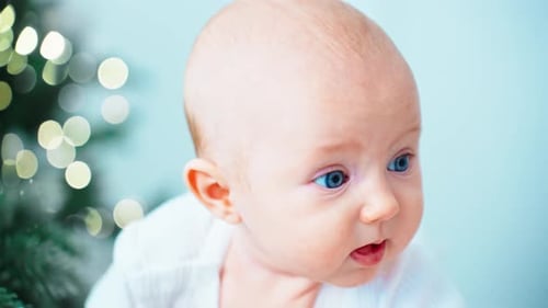 Adorable Infant Lying Near Sparkling Christmas Tree Lights