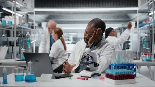Scientist Working at Desk with Microscope in Lab