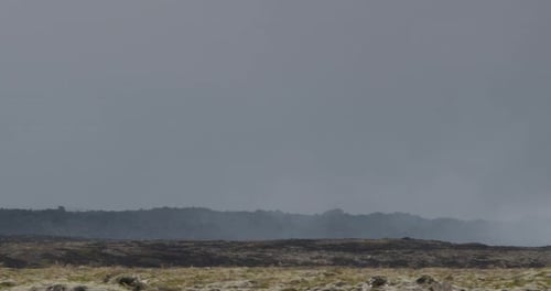 Pan left revealing the volcanic landscape of Grindavik, Iceland, with the erupting Sundhnúkur crater