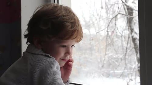 Child Looks Out Window at Snowfall