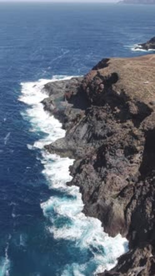 Volcanic Cliffs of La Palma Withstanding Powerful Ocean Waves in a Vertical Video Dark Basalt