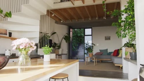 General view of modern kitchen and living room with countertop, sofa and staircase