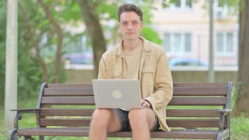 Man Works on Laptop on Park Bench