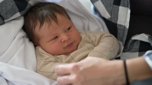 Close-up of newborn baby resting on mother’s lap, highlighting the peaceful and serene moments of