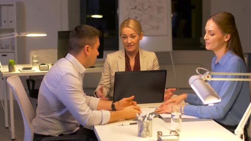 Colleagues Brainstorming Together in Bright Office at Night