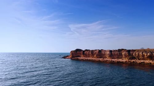 Quick flight over the vast blue waterscape. Approaching the rocky shore with steep cliffs