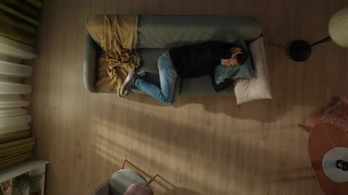 Top View of a Man Lying on a Couch in the Living Room Man Rubs His Temples Suffering From Severe