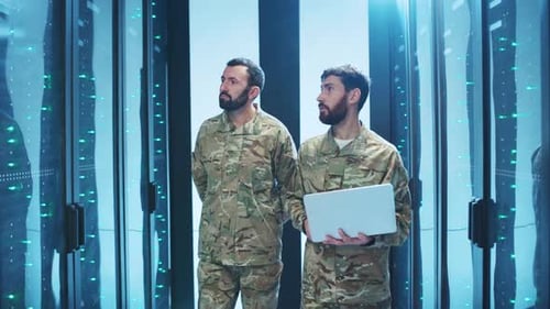Two men working in server room using laptop
