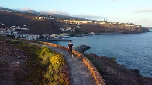 Drone shot young man walking on coastal mountain path Canary Island