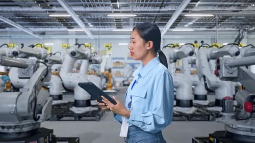 Woman with Tablet Inspecting Rows of Robots in Factory