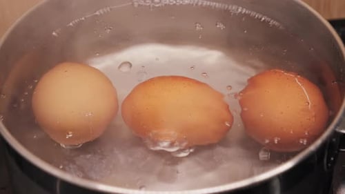 Nahaufnahme von Hühnereiern, die in einer Edelstahlpfanne kochen Eier kochen, leckere Ernährung und Protein, gesundes Essen