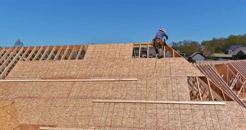 Work Being Done By a Carpenter Roofer on Putting Plywood Over an Unfinished Houses Roof
