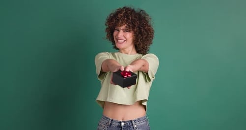 Surprised Woman Opening Gift Box in Green Colored Studio