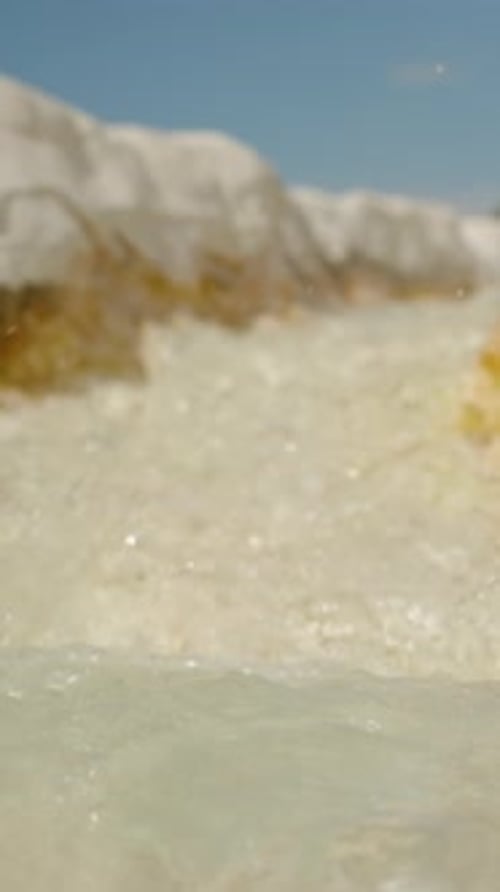 Vertical video. White Stone Gutter through which Water Flows from a Spring, with Calcite Stalactites