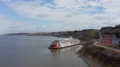 Wide panning aerial shot of the river cruise ship American Queen docked at the Port of Natchez in Mi