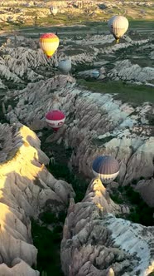 Vertical Video Hot Air Balloons Fly Over the Mountainous Landscape of Cappadocia Turkey