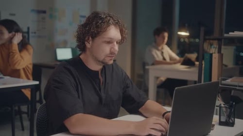 Man Using Laptop and Posing on Camera in Office at Night