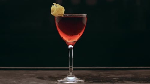Close up negroni cocktail garnished on a dark bar counter