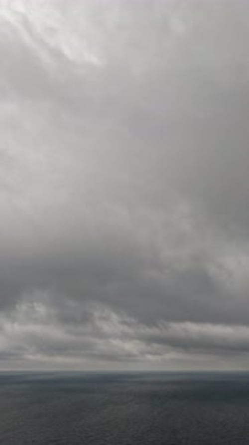 Timelapse Nuages de nimbostratus pluvieux se déplaçant dans un ciel lumineux au coucher du soleil au-dessus d'une mer orageuse, vue aérienne abstraite