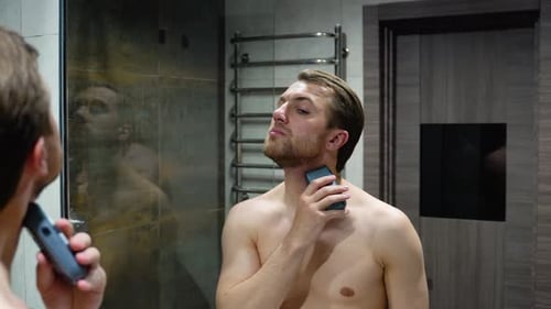 Man Shaving Beard in Bathroom Mirror