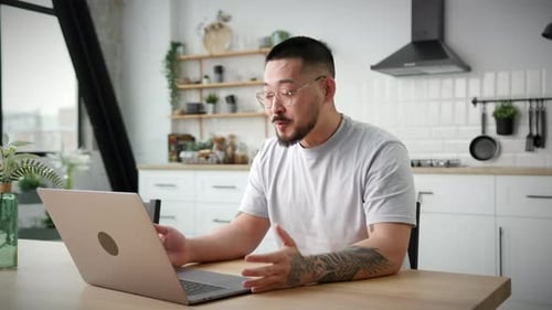 Young Adult Using Laptop For Video Call in Kitchen