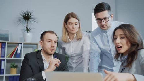 Team of Professionals Collaborating on Laptop in Office