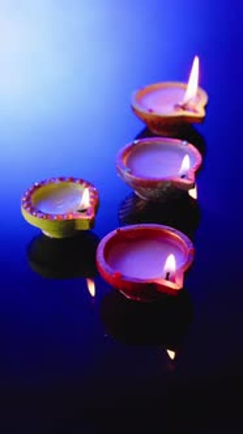 Vidéo verticale de bougies allumées célébrant Diwali sur fond bleu, avec espace de copie