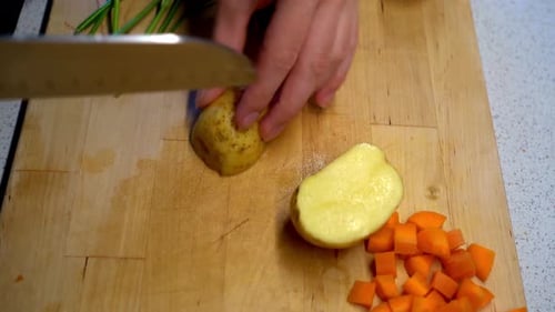 Cutting potatoes and carrots on cutting board