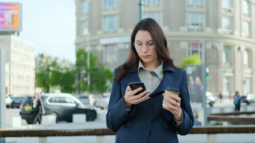 Woman Uses Phone With Coffee in City