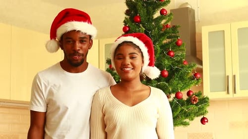 Happy Couple Waving with Santa Hats at Christmas