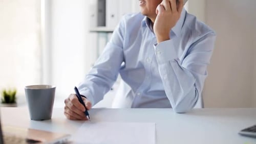 Smiling businessman at office talking on smartphone for communication technology