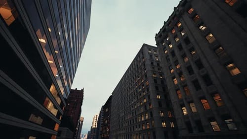 Calle silenciosa de la ciudad con estructuras imponentes y un ambiente cambiante visto desde abajo