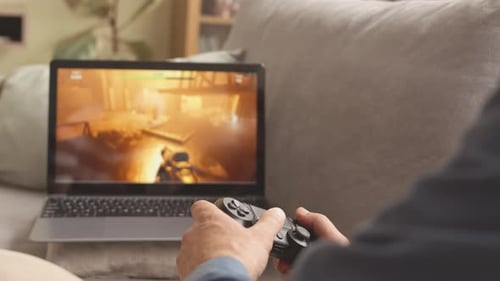 Adult Gaming on Laptop with Controller at Home