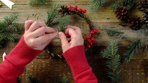 Woman Hands Making Christmas Wreath on Wooden Table