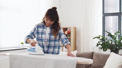 Woman ironing gray cloth on ironing board