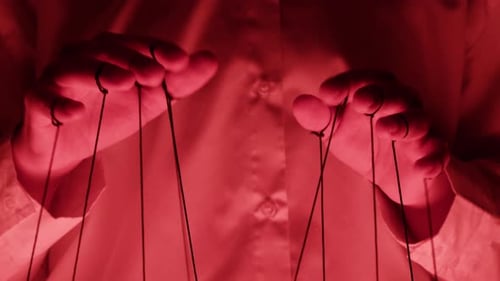 The Puppeteer Controls the Puppets in the Theater in Red Neon Light Closeup Managing People at Work