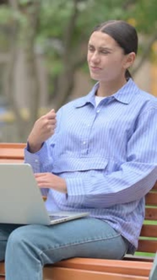 Woman Using Laptop On Park Bench Outside