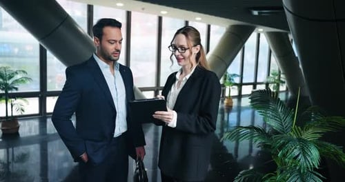 Two Business Professionals Stand And Discuss Work In The Office Hallway. - medium shot