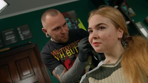 Piercing studio interior - piercing master makes a piercing to a girl, ear piercing