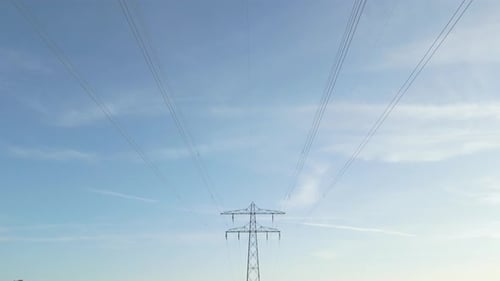 Aerial drone shot of Power Line Tower With Electricity Cables Across Farmland