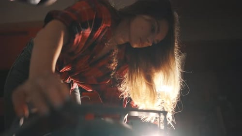Woman Working on a Machine in a Dark Workshop