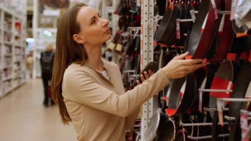Young Beautiful Woman Choosing Frying Pan Utensil Dishes in a Store Supermarket Shop